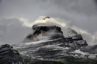 白天灰色和黑色崎岖山脉和云层的低角度照片